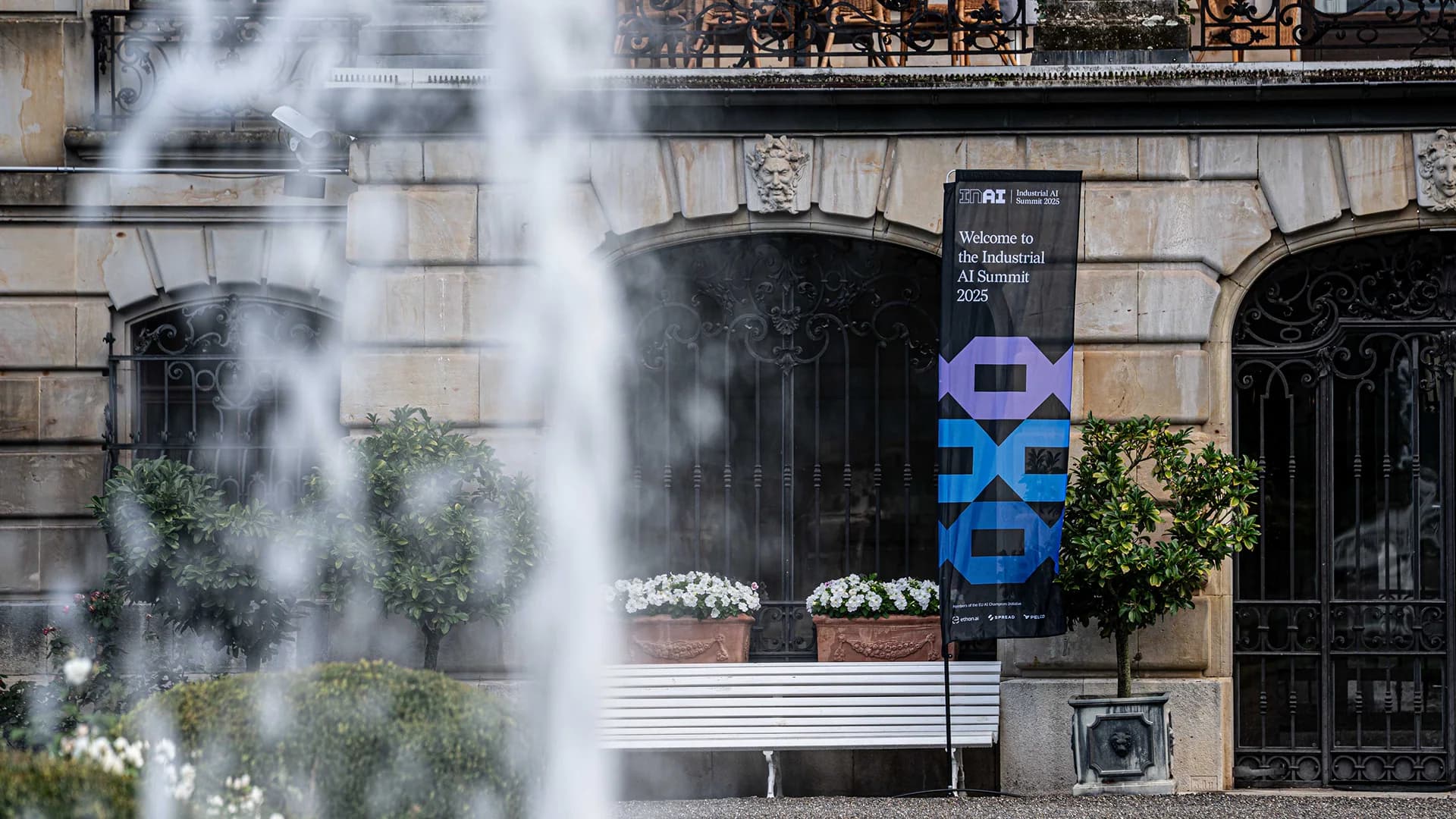 Industrial AI Summit 2025 welcome banner seen through the Schloss Donaueschingen fountain